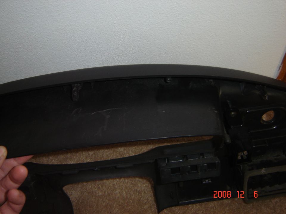 Black plastic dashboard trim piece with mounting holes and clips visible