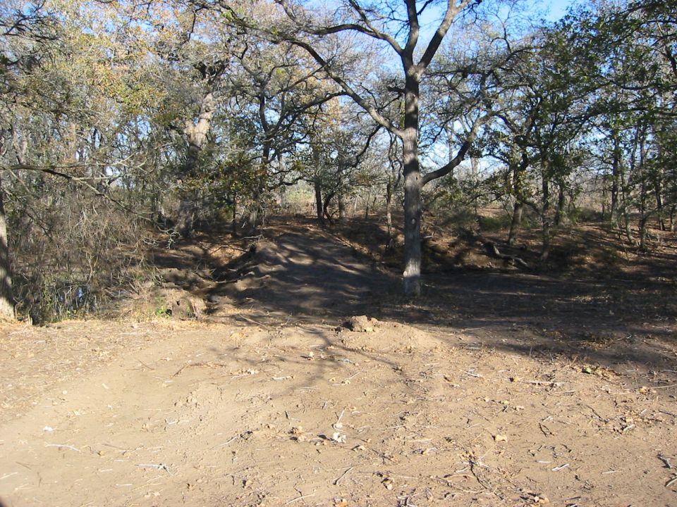 Dirt path winding through trees with a "SUPERMOTORS" watermark