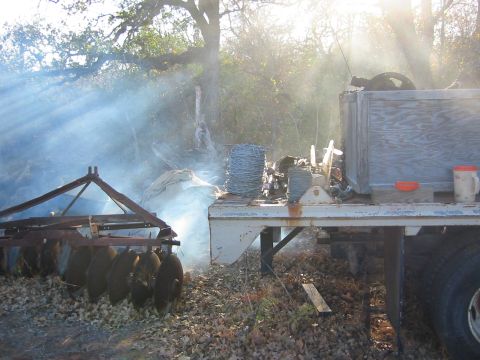 1996 Ford Bronco - A trailer carries barbed wire and farm equipment, with smoke rising in a rural outdoor setting.