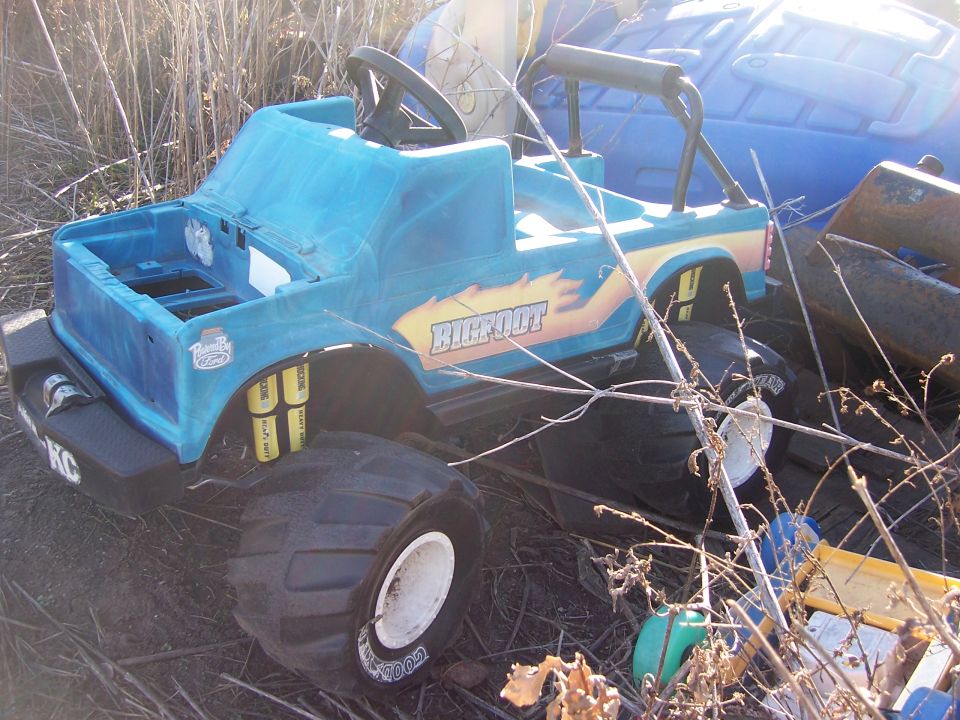 Blue toy Bigfoot monster truck with large tires, sitting in dry grass