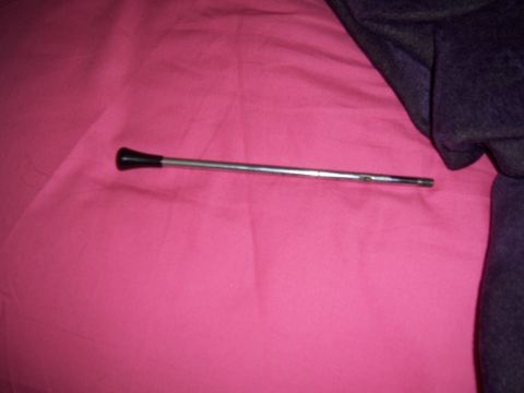 1979 Ford Bronco - A chrome shift lever with a black knob lies on a pink surface next to dark fabric.