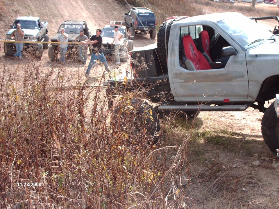 Pickup truck with red seats and spare tire on back, being pulled by rope