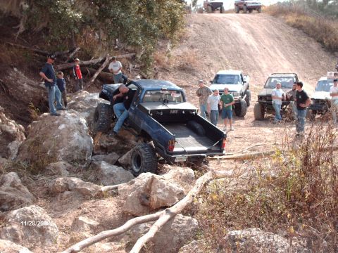 1982 Ford F-100 - Several off-road vehicles and spectators gather on a challenging rocky terrain during an event.