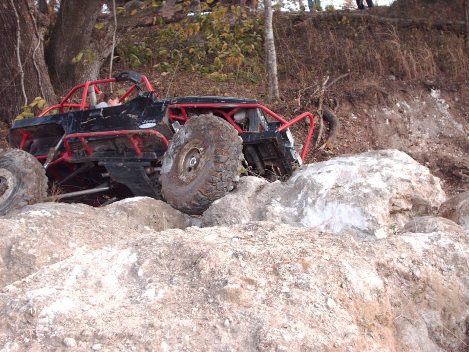 Off-road buggy with red roll cage navigating rocky terrain
