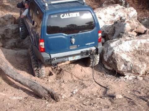1982 Ford F-100 - SUV with a winch cable attached to a rock, attempting to maneuver through difficult terrain.