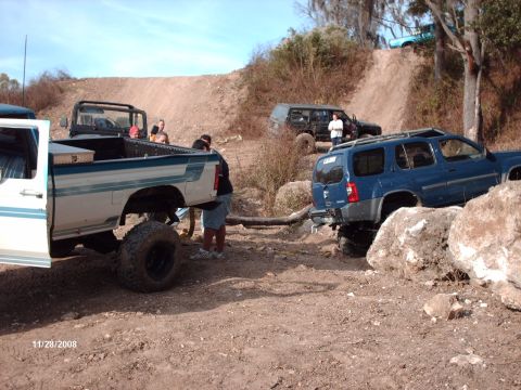 1982 Ford F-100 - Several off-road vehicles navigate a rocky, hilly terrain on a sunny day.