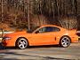 1995 Ford Mustang - Side view of an orange 1995 Ford Mustang coupe parked outdoors.