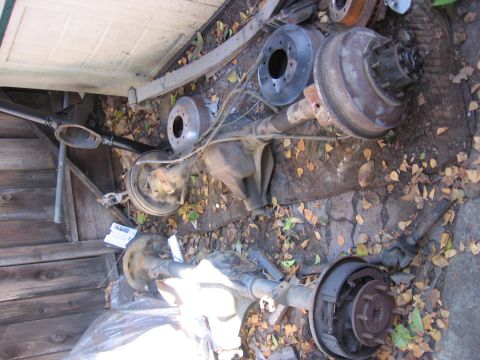 1989 Ford Bronco - Two vehicle axles, likely from a truck or SUV, are stored outdoors amongst fallen leaves.