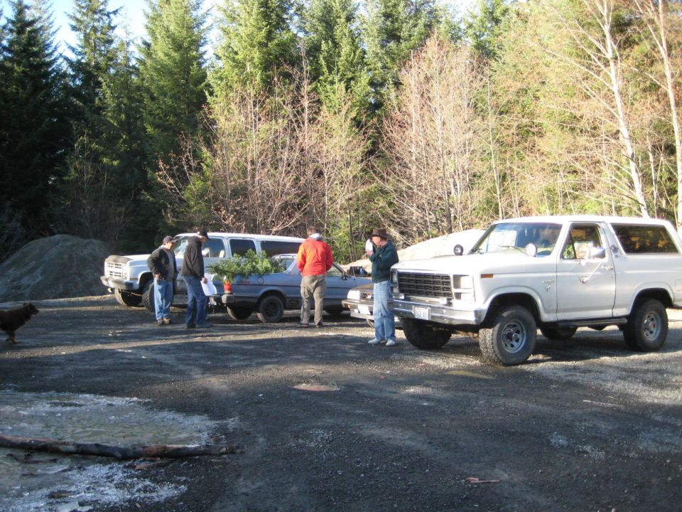 1980 Ford Bronco parked next to a sedan and a van, with people nearby