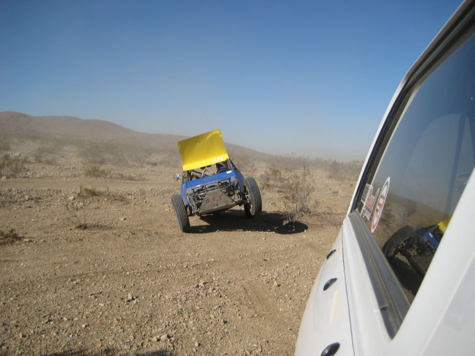 Off-road buggy with yellow hood tilted on dusty terrain