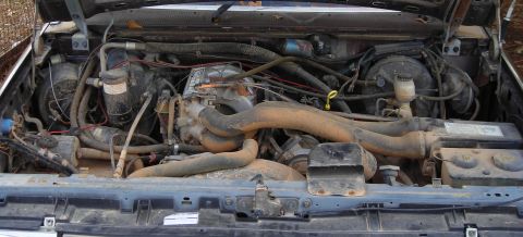 1988 Ford Bronco - The engine bay of a 1988 Ford Bronco shows a complex arrangement of hoses and wiring.
