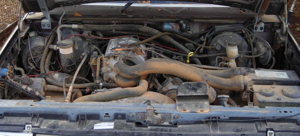1988 Ford Bronco engine bay with visible hoses, wiring, and engine components