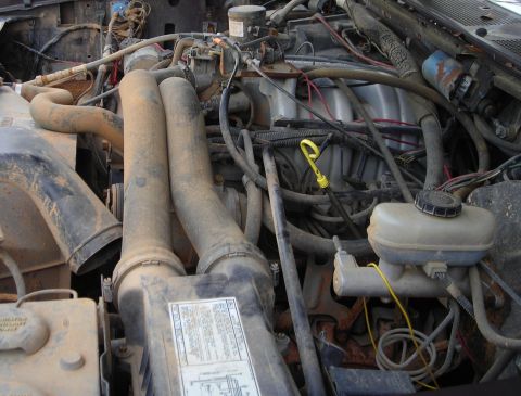 1988 Ford Bronco - Close-up view of a dusty engine bay with various components and wiring visible.