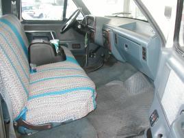 1991 Ford C-350 (Centurion Conversions) - The interior of a van shows a bench seat with a striped pattern and the dashboard area.
