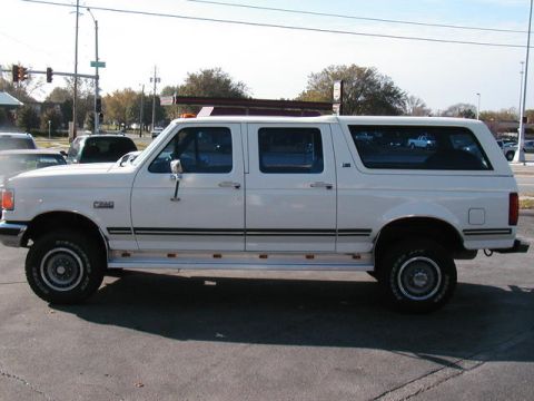 1991 Ford C-350 (Centurion Conversions) - This white extended cab pickup truck features a camper shell, giving it a unique, elongated SUV-like appearance.