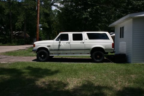 1991 Ford C-350 (Centurion Conversions) - This 1991 Ford C-350 Centurion Conversions extended cab pickup truck is seen parked on a grassy area next to a white building.