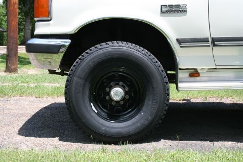 1991 Ford C-350 (Centurion Conversions) - Close-up of the front wheel and fender of a white 1991 Ford C-350 (Centurion Conversions) truck, showing the C350 badge.