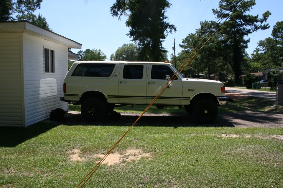1991 Ford C-350 (Centurion Conversions) extended cab pickup truck parked next to a white building