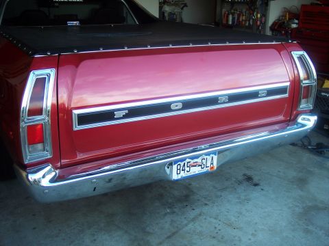 1972 Ford Ranchero - The rear of a red Ford pickup truck is shown, a chrome bumper and the Ford nameplate across the tailgate.