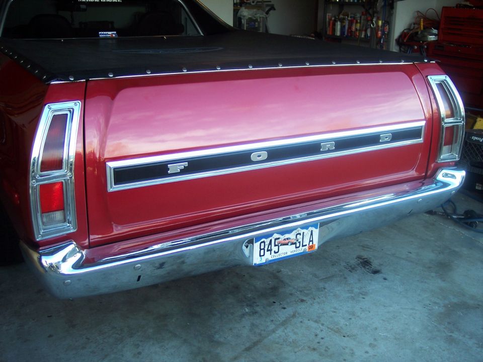 Rear of a red Ford with chrome bumper and 'FORD' tailgate badge in a garage