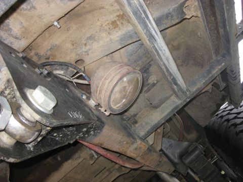 1979 Ford Bronco - A close-up shot of a rock light mounted to the undercarriage of a vehicle, with visible suspension parts.