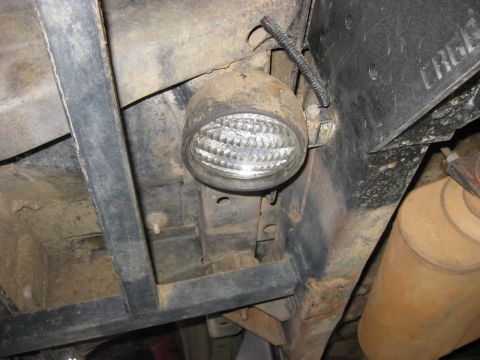 1979 Ford Bronco - A close-up view of the undercarriage of a vehicle, focusing on a mounted rock light and exhaust system.