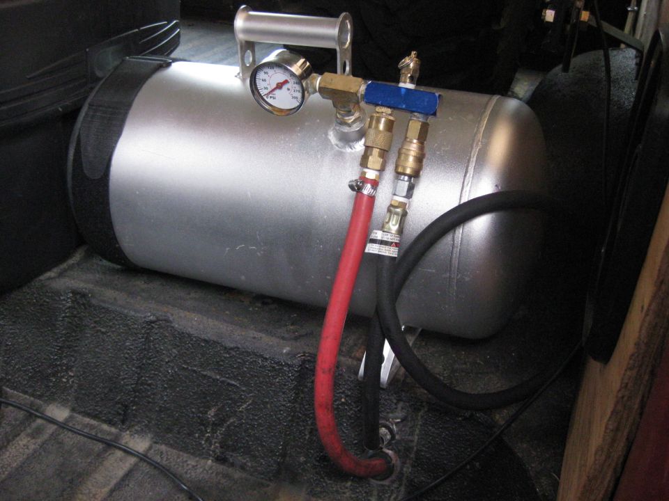 Silver air compressor tank with pressure gauge and red/black hoses