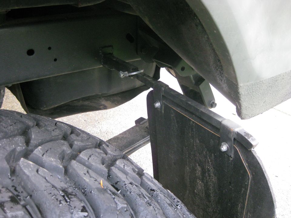 Mud flap attached to vehicle frame near tire