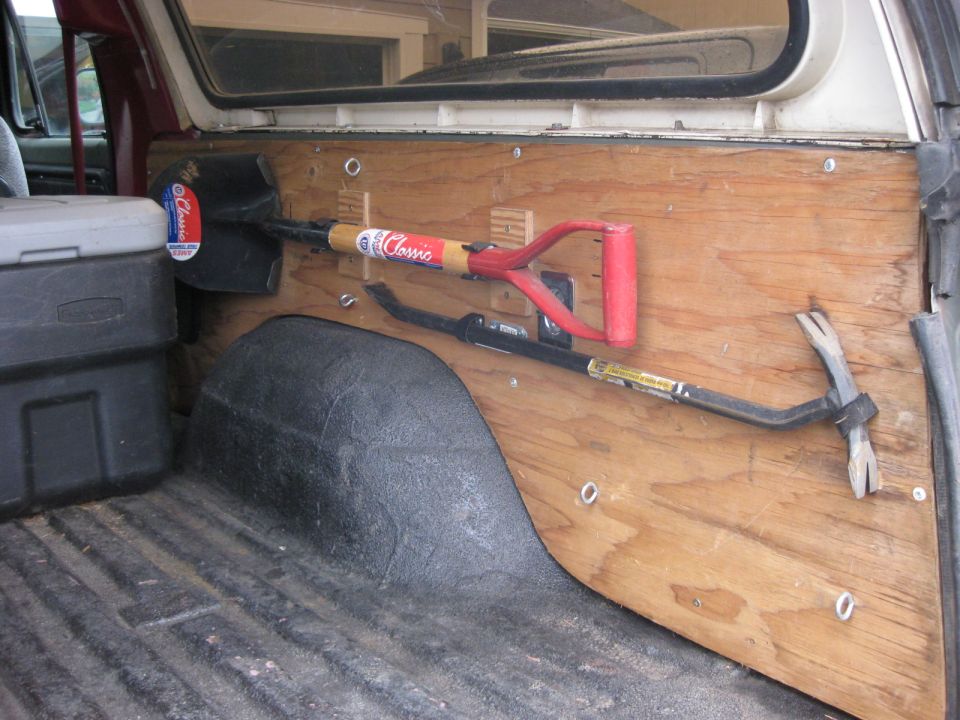 Interior view of a vehicle with a shovel and crowbar mounted on a wooden panel