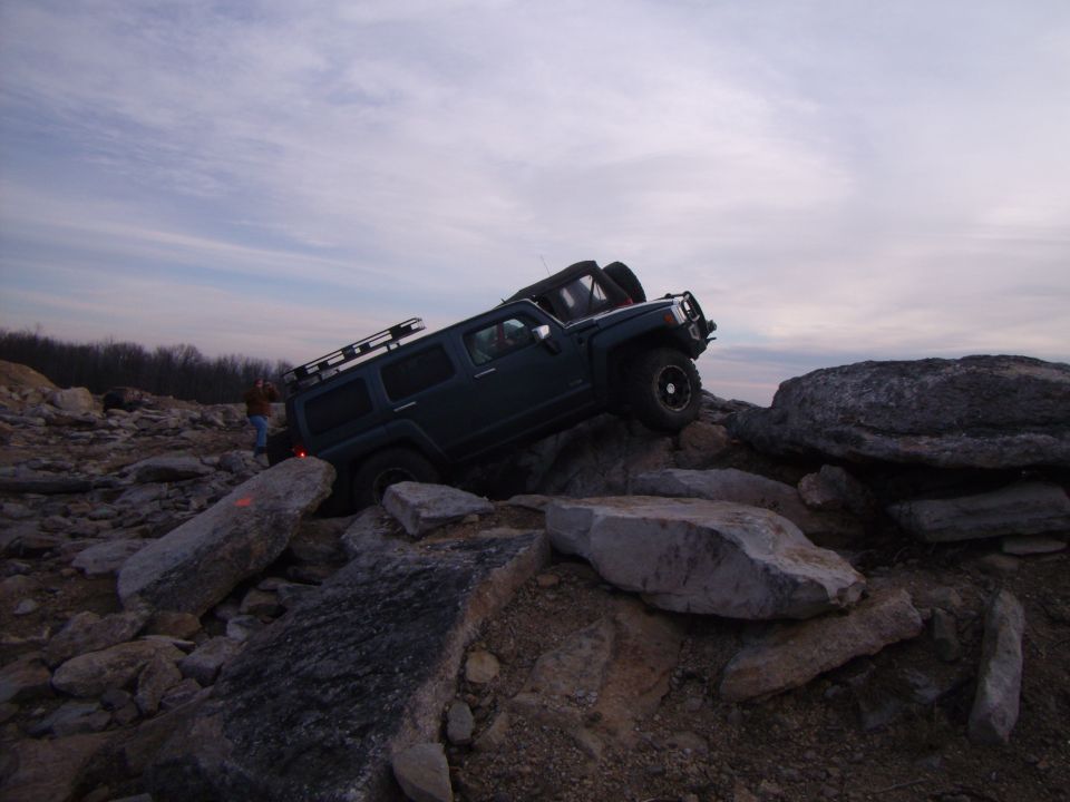 Dark SUV with roof rack navigating a rocky terrain