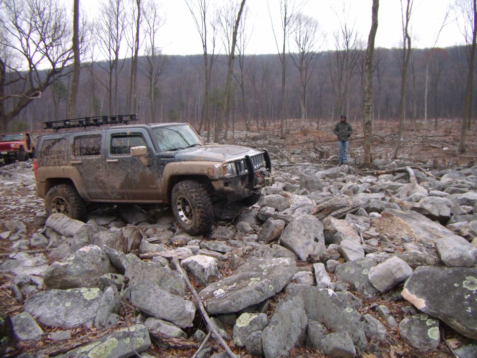 Muddy 2005 Hummer H3 off-roading over large rocks