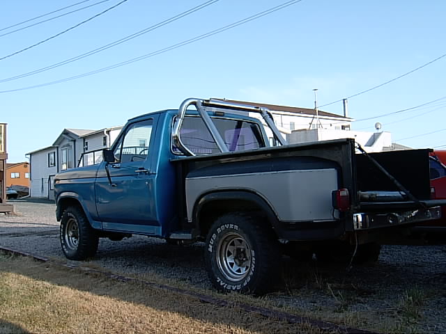 Blue 1980s pickup truck, 3/4 front view, with roll bar