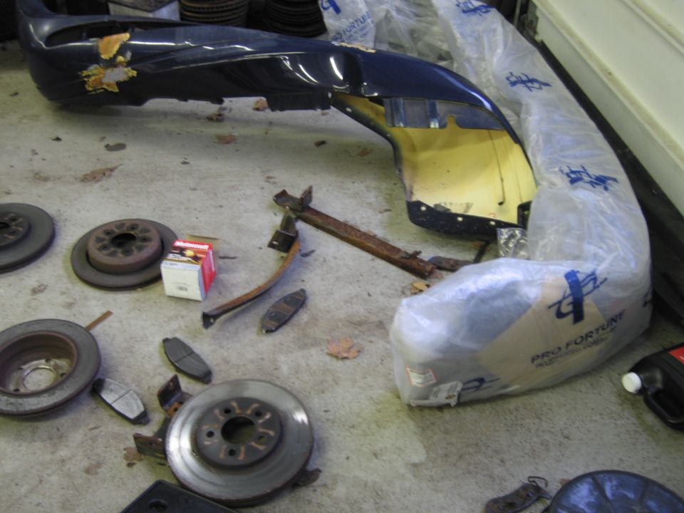 Dark blue bumper and brake rotors and pads on concrete floor