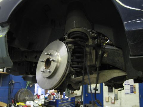 2001 Ford Crown Victoria - Vehicle's front brake system, including rotor and caliper, is visible while the car is elevated.