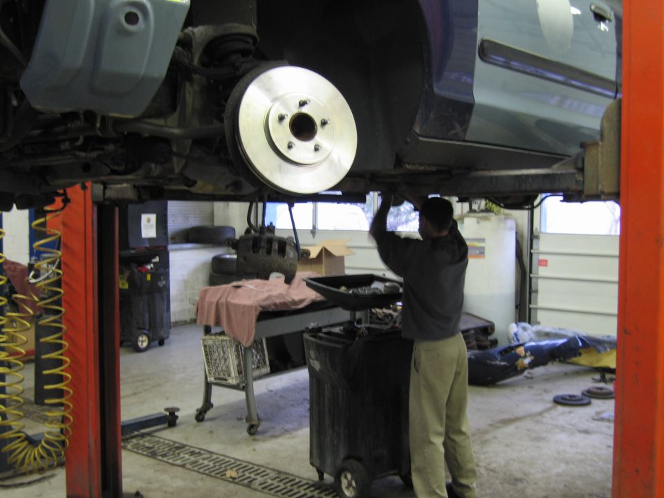 Car brake rotor being serviced by a mechanic in a garage