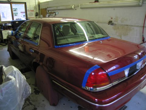2001 Ford Crown Victoria - A maroon 2001 Ford Crown Victoria is parked in a garage, with blue painter's tape applied to the rear of the vehicle.