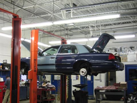2001 Ford Crown Victoria - A 2001 Ford Crown Victoria is being serviced in a garage, with its hood and trunk open.