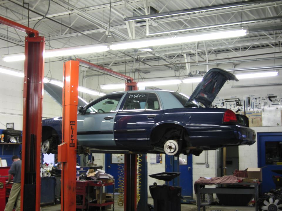 2001 Ford Crown Victoria on a lift with hood and trunk open, showing two-tone paint job