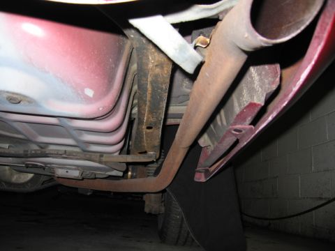 2001 Ford Crown Victoria - Undercarriage view of a vehicle's exhaust system and rear tire, showing signs of rust.