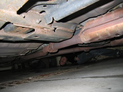 2001 Ford Crown Victoria - Underbody view of a car with a person inspecting the exhaust and chassis components.