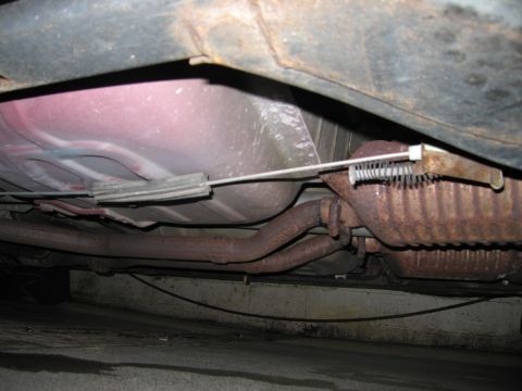 2001 Ford Crown Victoria - The undercarriage of a vehicle reveals its exhaust system, fuel tank, and brake lines.