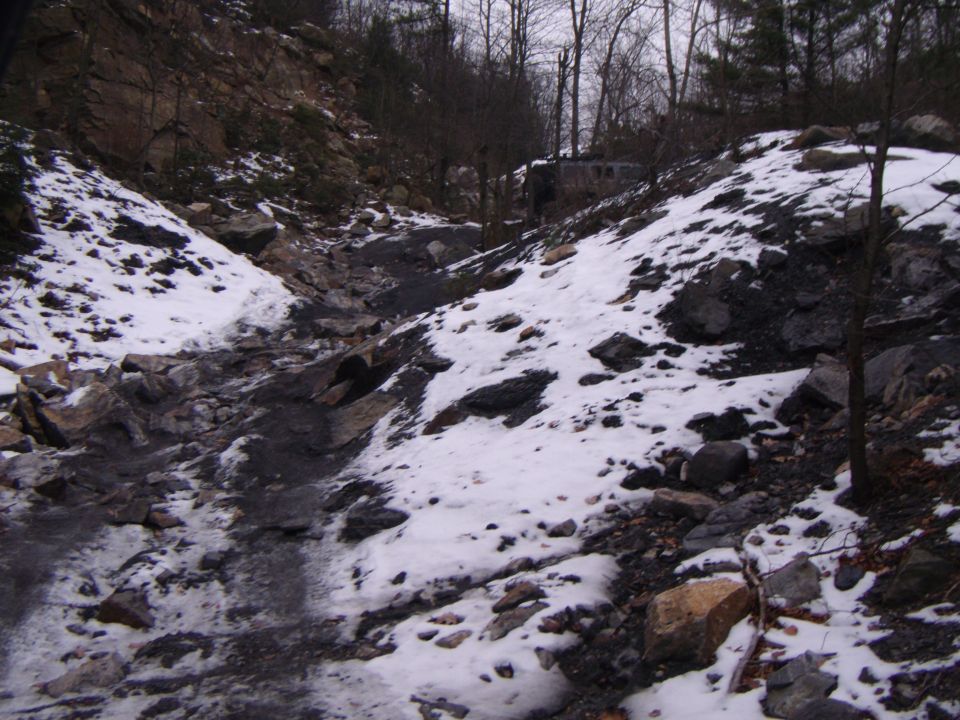 Off-road vehicle parked on a snowy hillside in a rocky ravine