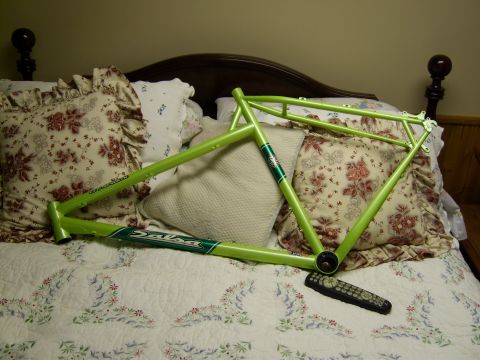 1972 Ford Ranchero - A green bicycle frame is laid out on a bed with pillows and a remote control.