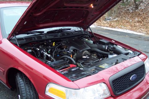 2001 Ford Crown Victoria - The engine compartment of a red Ford Crown Victoria is displayed with the hood raised.