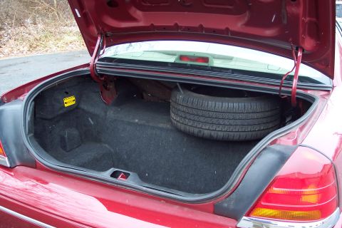2001 Ford Crown Victoria - The trunk of a red 2001 Ford Crown Victoria contains a spare tire and carpeting.