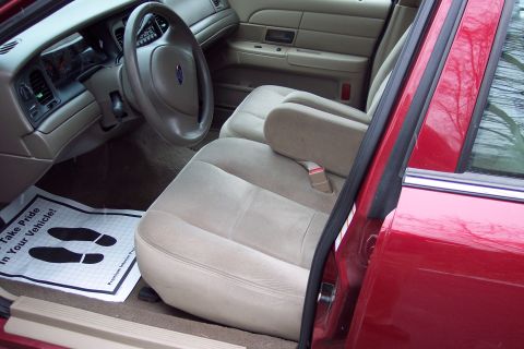 2001 Ford Crown Victoria - The interior of a 2001 Ford Crown Victoria features tan cloth seats and a floor mat with footprints.