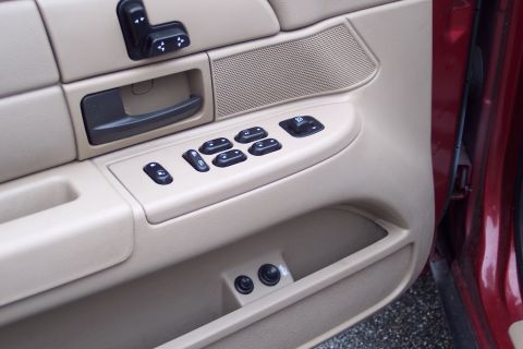 2001 Ford Crown Victoria - The interior door panel of a vehicle shows multiple power window controls and a speaker grille.