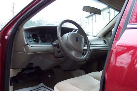 2001 Ford Crown Victoria - Interior view of a red Ford Crown Victoria, showing the dashboard, steering wheel, and tan seats.