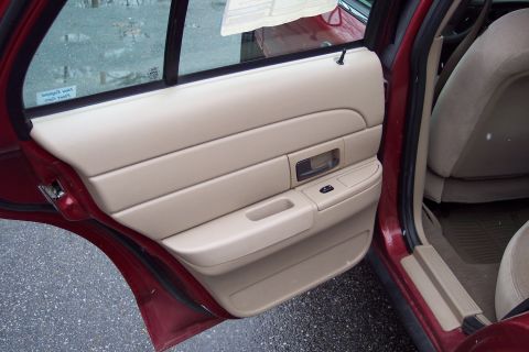2001 Ford Crown Victoria - The tan interior door panel of a 2001 Ford Crown Victoria is visible, along with the front passenger seat.
