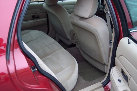 2001 Ford Crown Victoria - Interior view of a red 2001 Ford Crown Victoria, highlighting the tan upholstery and door trim.